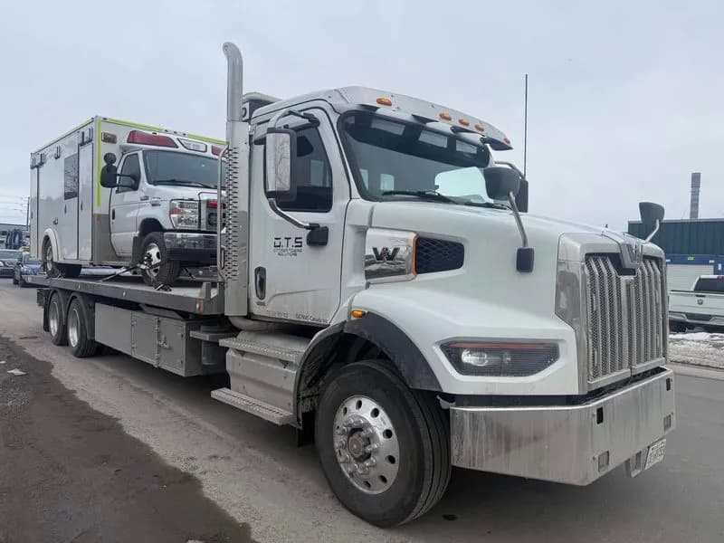 OTS flatbed tow truck loaded with a service vehicle in winter