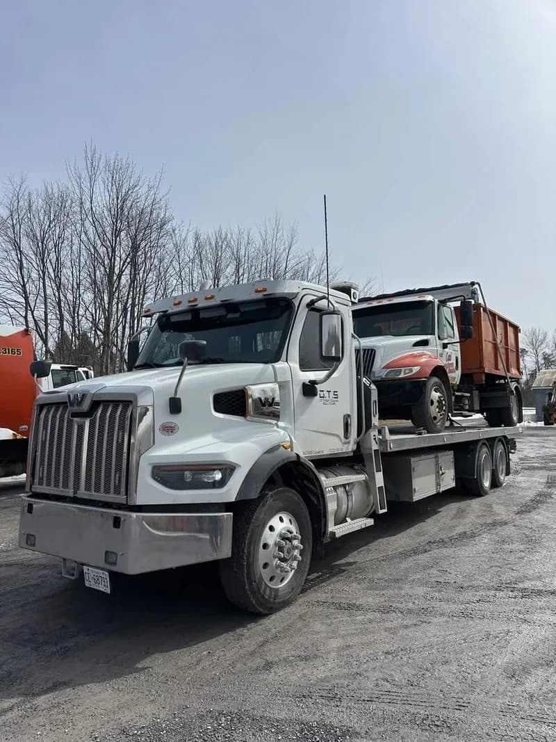Ottawa Towing Solutions hauling a dump truck on a flatbed