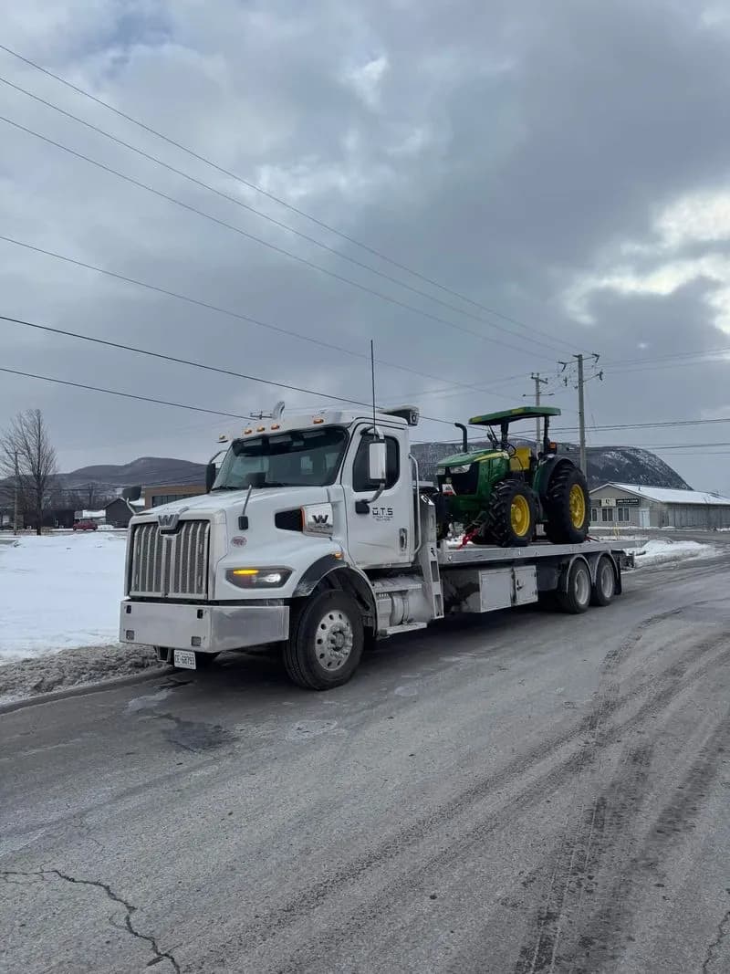 Ottawa Towing Solutions transporting a John Deere tractor in winter